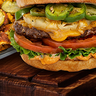 An iniBurger halal burger served on a wooden board with wings and loaded fries