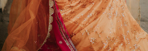 Close-up of a red and gold embroidered wedding outfit with an orange dupatta at a Muslim wedding