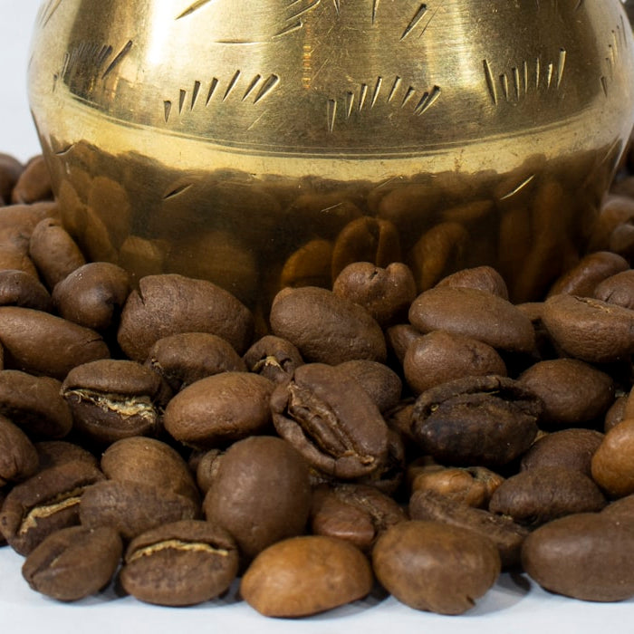 Traditional brass Arabic coffee dallah surrounded by roasted coffee beans