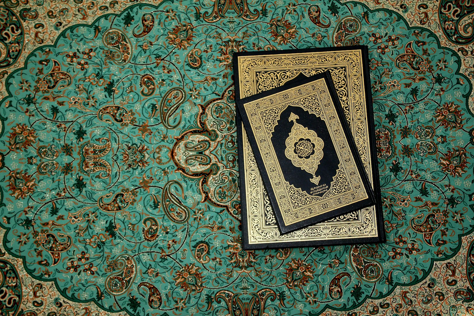 A Quran resting on an ornate turquoise prayer rug
