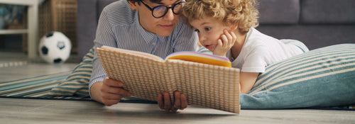 A mother and child lying on the floor reading a book together