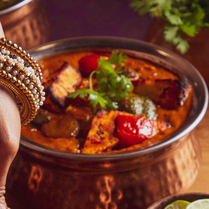 A South Asian dinner spread with curries, naan and kebabs in copper bowls