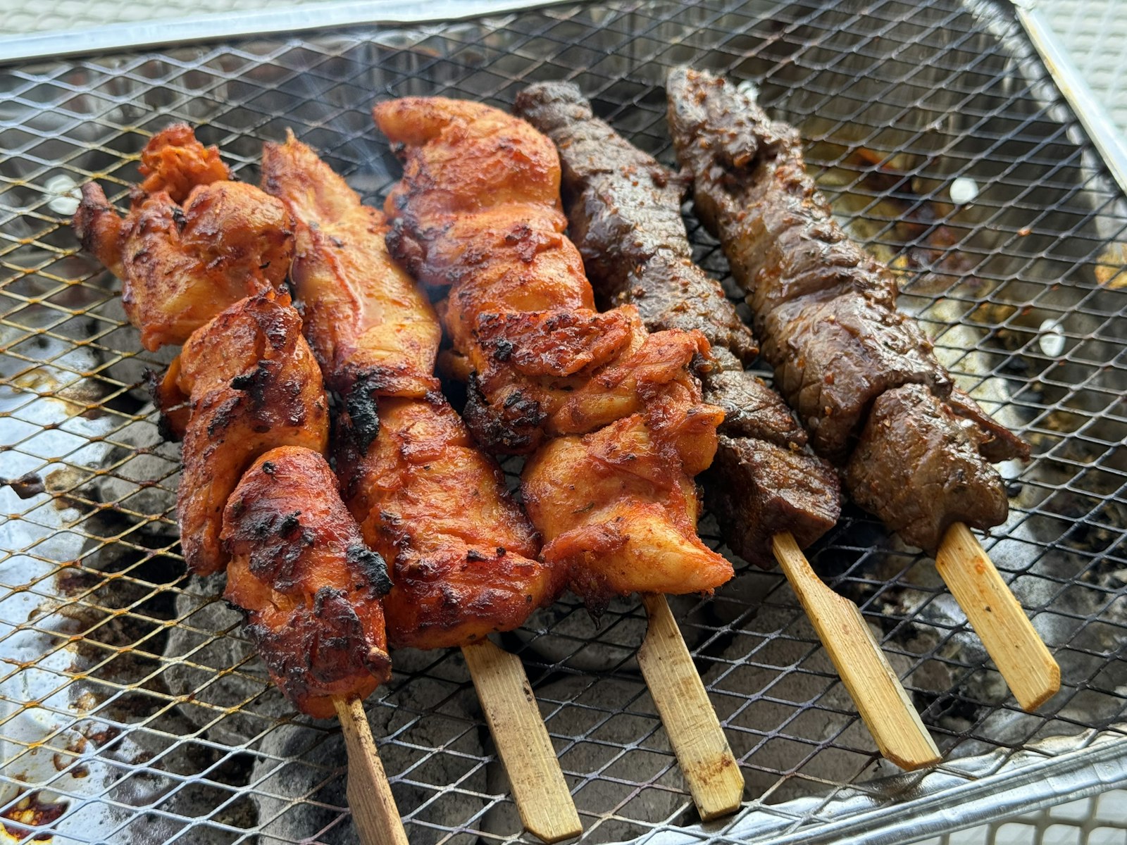Chicken and beef kebab skewers grilling over hot coals