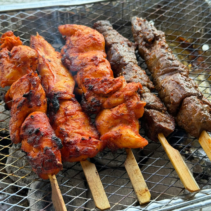 Chicken and beef kebab skewers grilling over hot coals